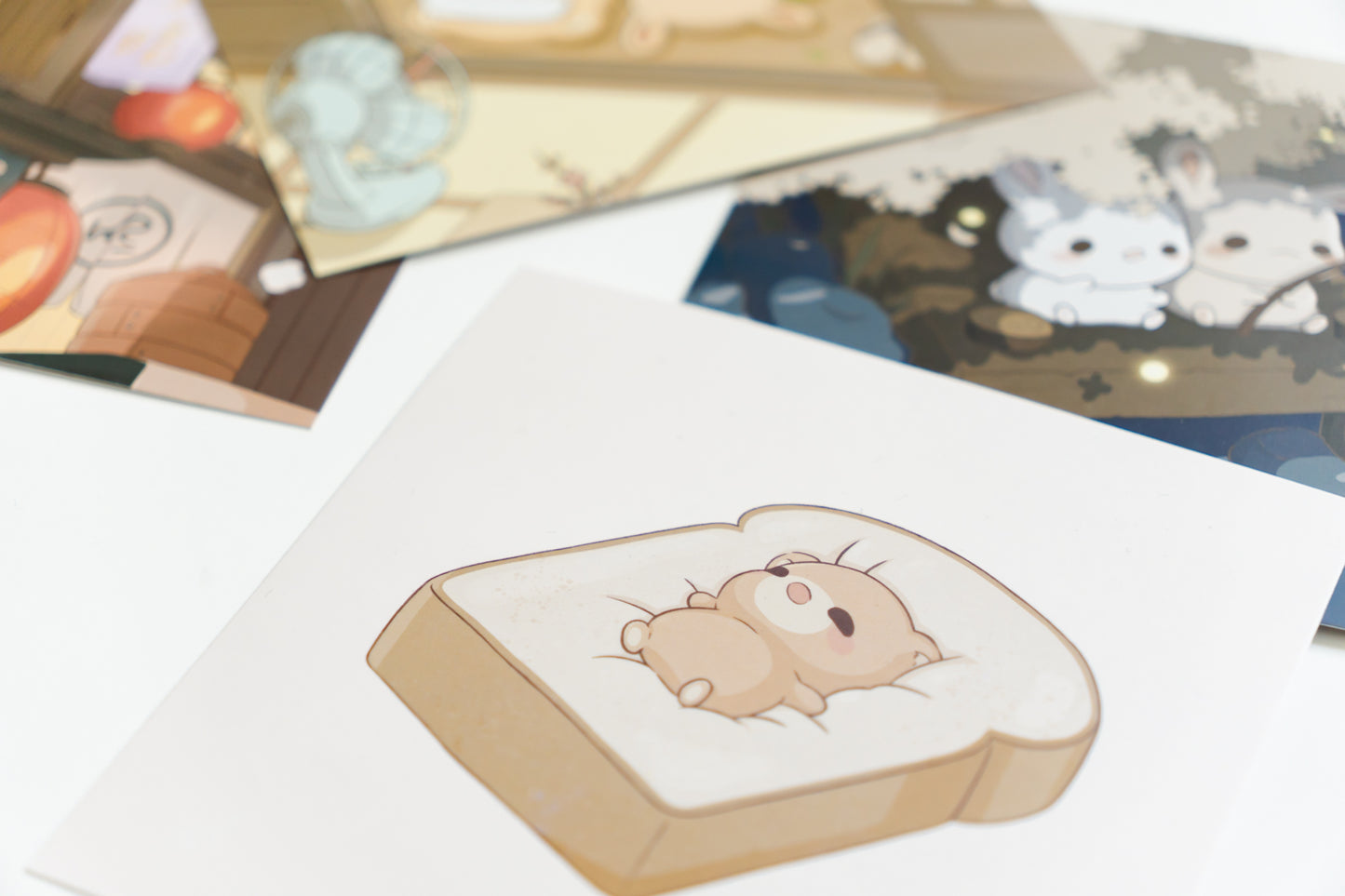 a 5.5"x5.5" square art print featuring a cute bear laying down on a piece of bread.