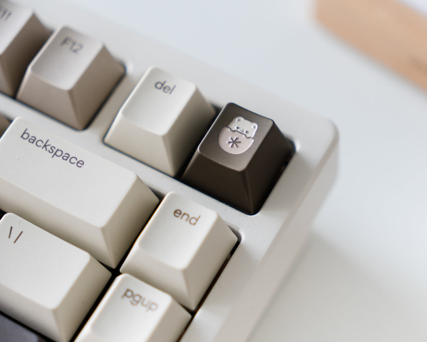 a brown metal keycap in cherry profile with a mocha cat design engraved on top.