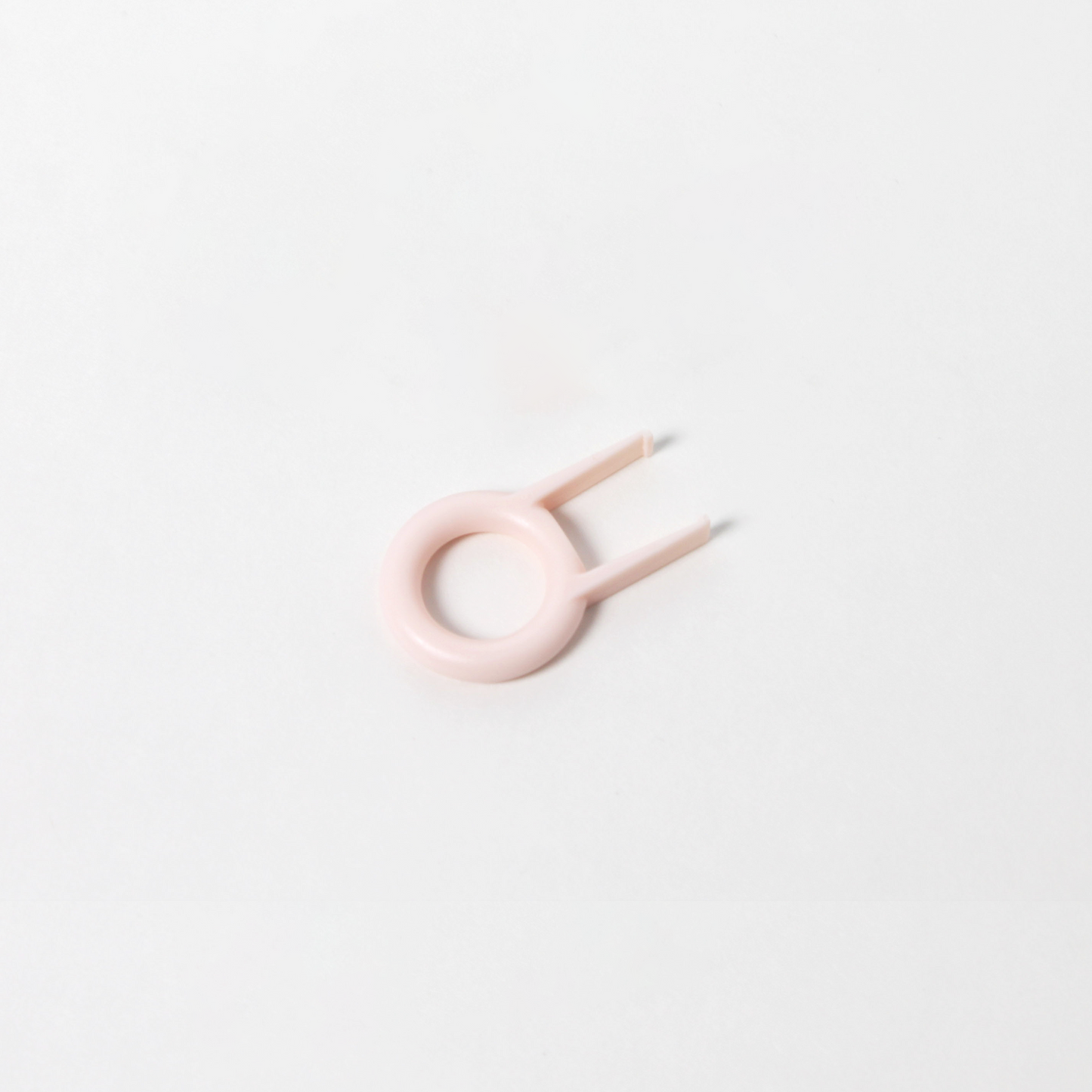 a basic petal pink keycap puller featuring a ring design with two prongs.