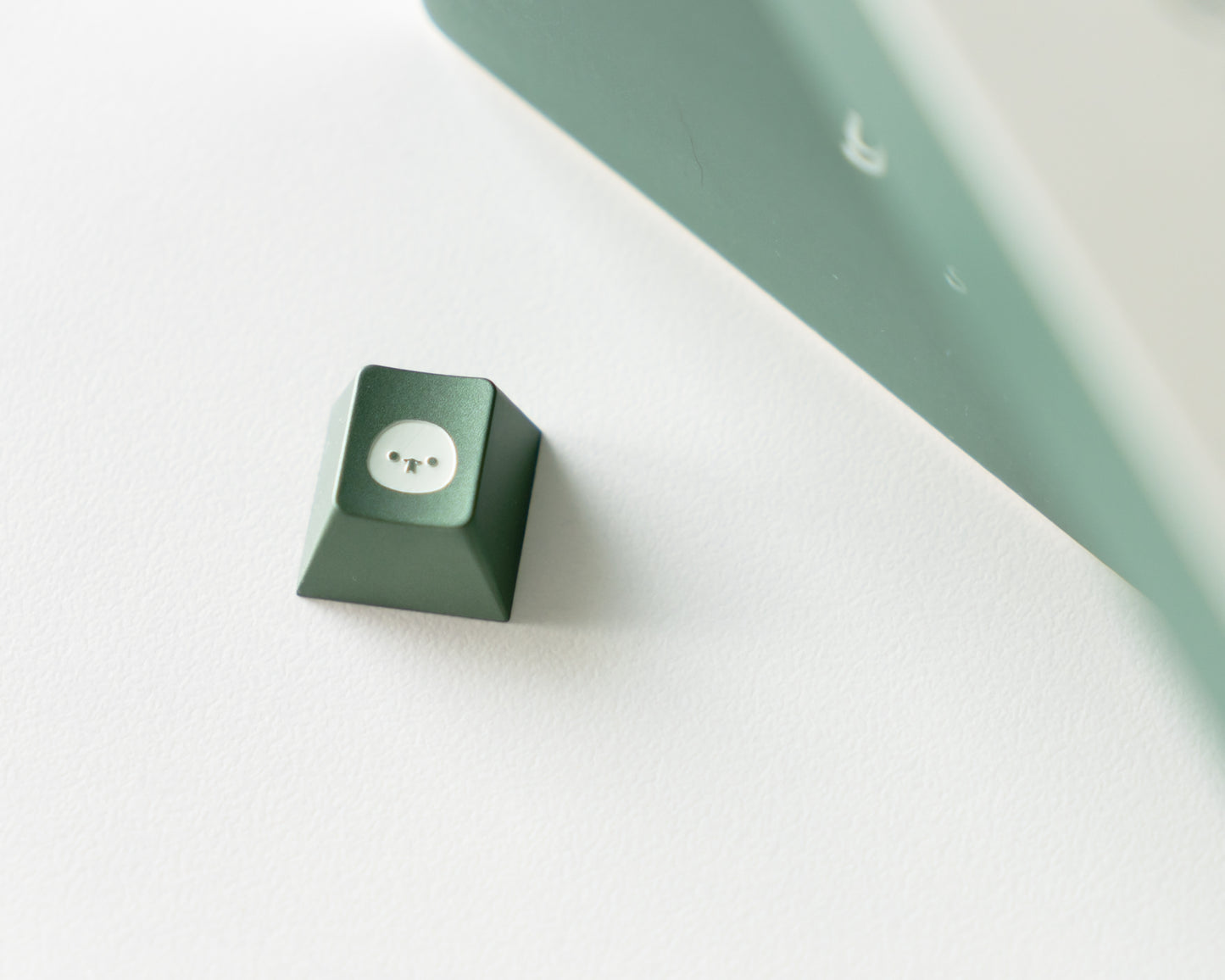 a green metal keycap in cherry profile with a snake design engraved on top.