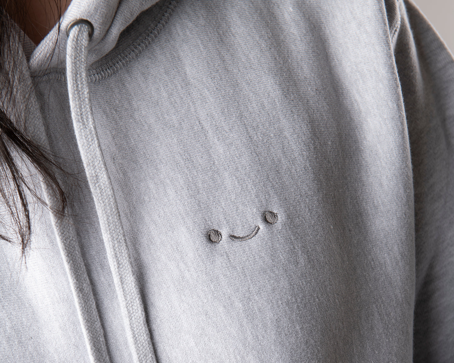 osume’s heavyweight hoodie in gray featuring an embroidered dark gray smiley face.