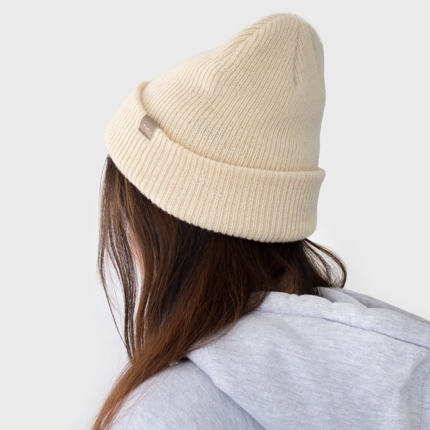 osume’s original wool beanie in the colour latte featuring a small brown smiley tag.