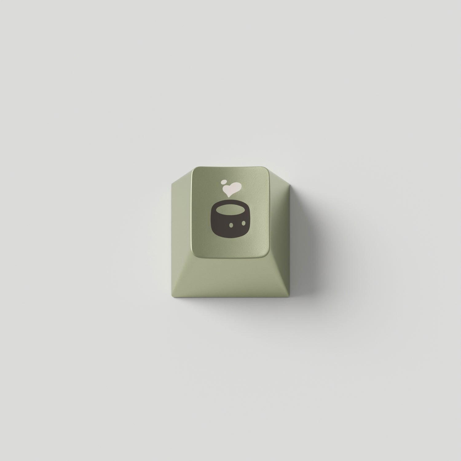 a green metal keycap in cherry profile with a cafe tea design engraved on top.